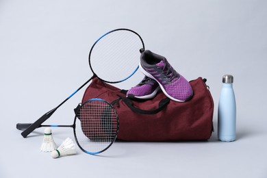 Badminton set, bag, sneakers and bottle on gray background