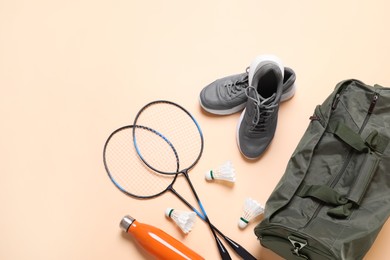 Badminton set, bag, sneakers and bottle on beige background, flat lay. Space for text