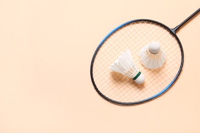 Feather badminton shuttlecocks and racket on beige background, top view. Space for text