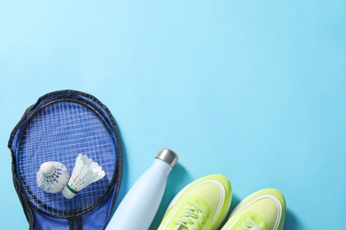 Photo of Badminton set, sneakers and bottle on light blue background, flat lay. Space for text