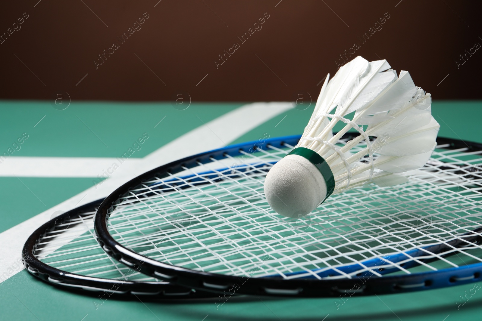 Photo of Feather badminton shuttlecock and rackets on court, closeup