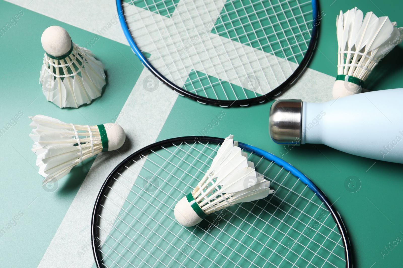 Photo of Feather badminton shuttlecocks, rackets and bottle on court, above view