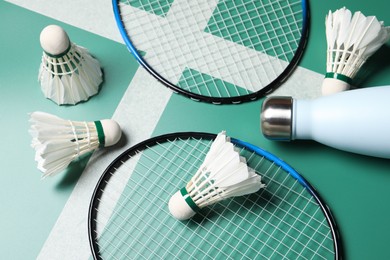 Photo of Feather badminton shuttlecocks, rackets and bottle on court, above view