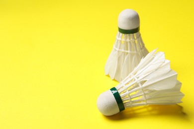 Photo of Feather badminton shuttlecocks on yellow background, space for text
