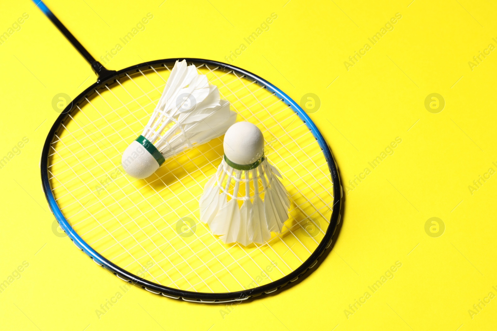 Photo of Feather badminton shuttlecocks and racket on yellow background