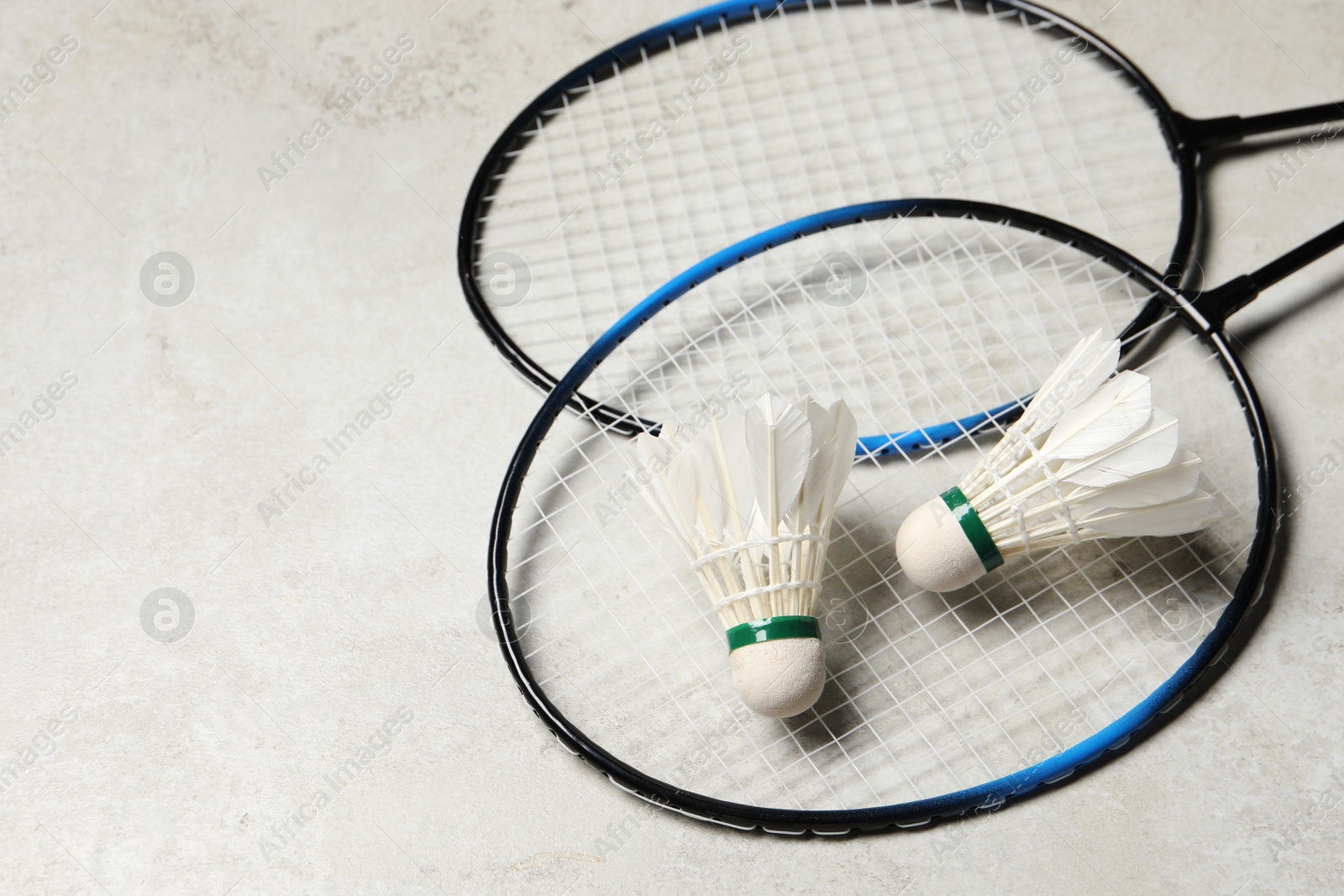 Photo of Feather badminton shuttlecocks and rackets on gray background, space for text