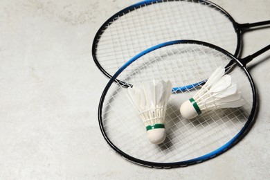 Feather badminton shuttlecocks and rackets on gray background, space for text