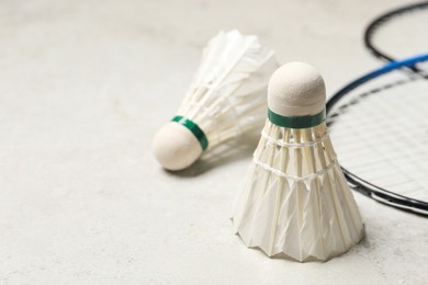 Photo of Feather badminton shuttlecocks and rackets on gray background, closeup. Space for text