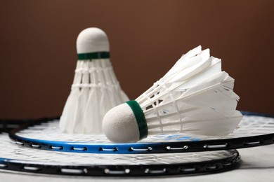 Photo of Feather badminton shuttlecocks and rackets on gray table against brown background, closeup