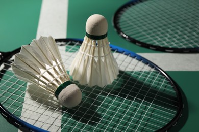 Feather badminton shuttlecocks and rackets on court, closeup