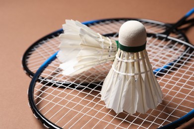 Feather badminton shuttlecocks and rackets on brown background, closeup