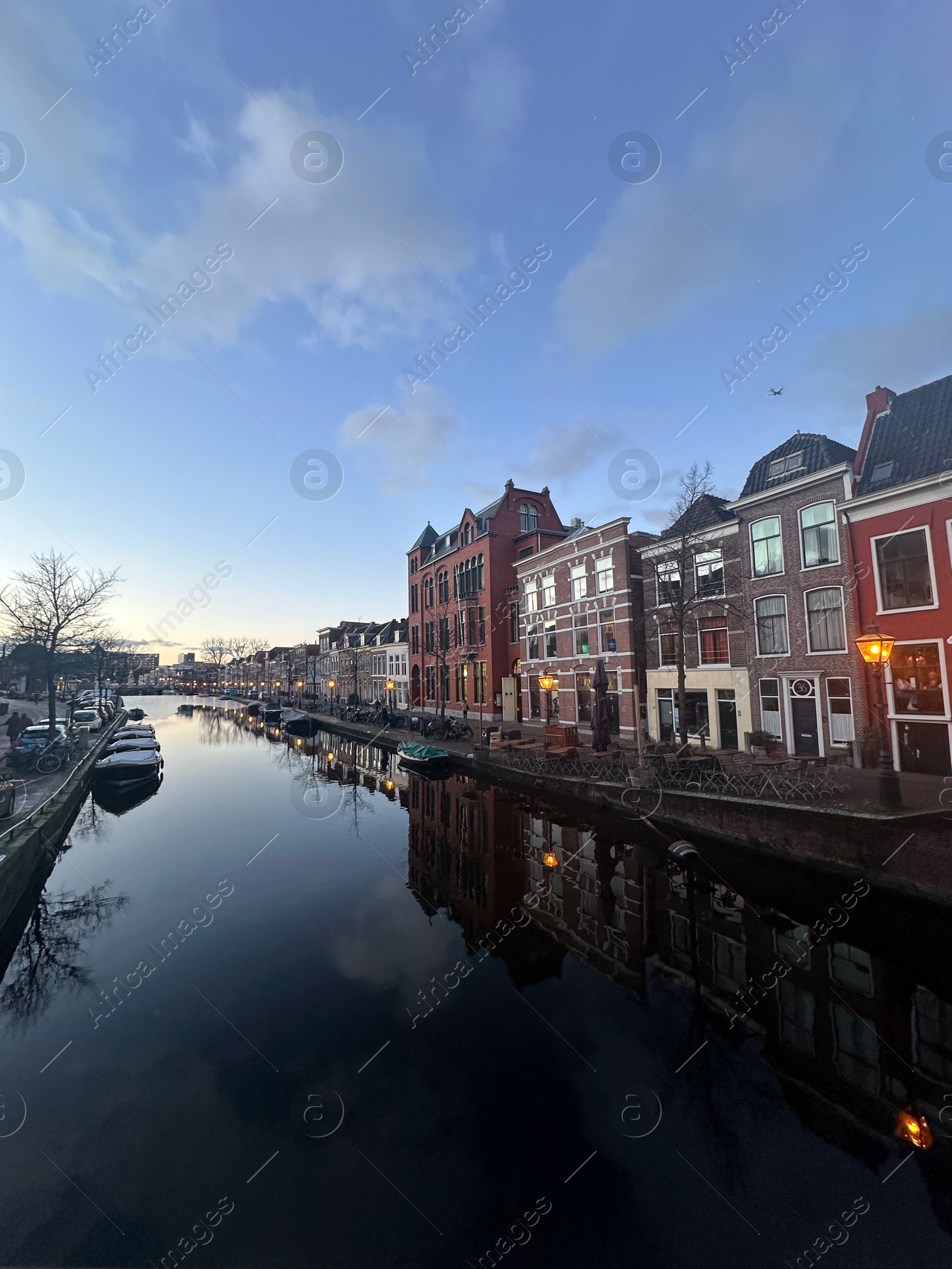 Photo of Beautiful view of canal with moored boats in city under blue sky