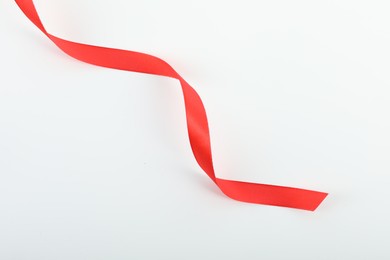 Photo of Beautiful red ribbon isolated on white, top view