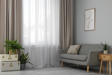 Photo of Comfortable sofa and elegant curtains in living room. Interior design