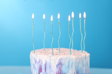 Tasty Birthday cake with burning candles on light blue background, closeup