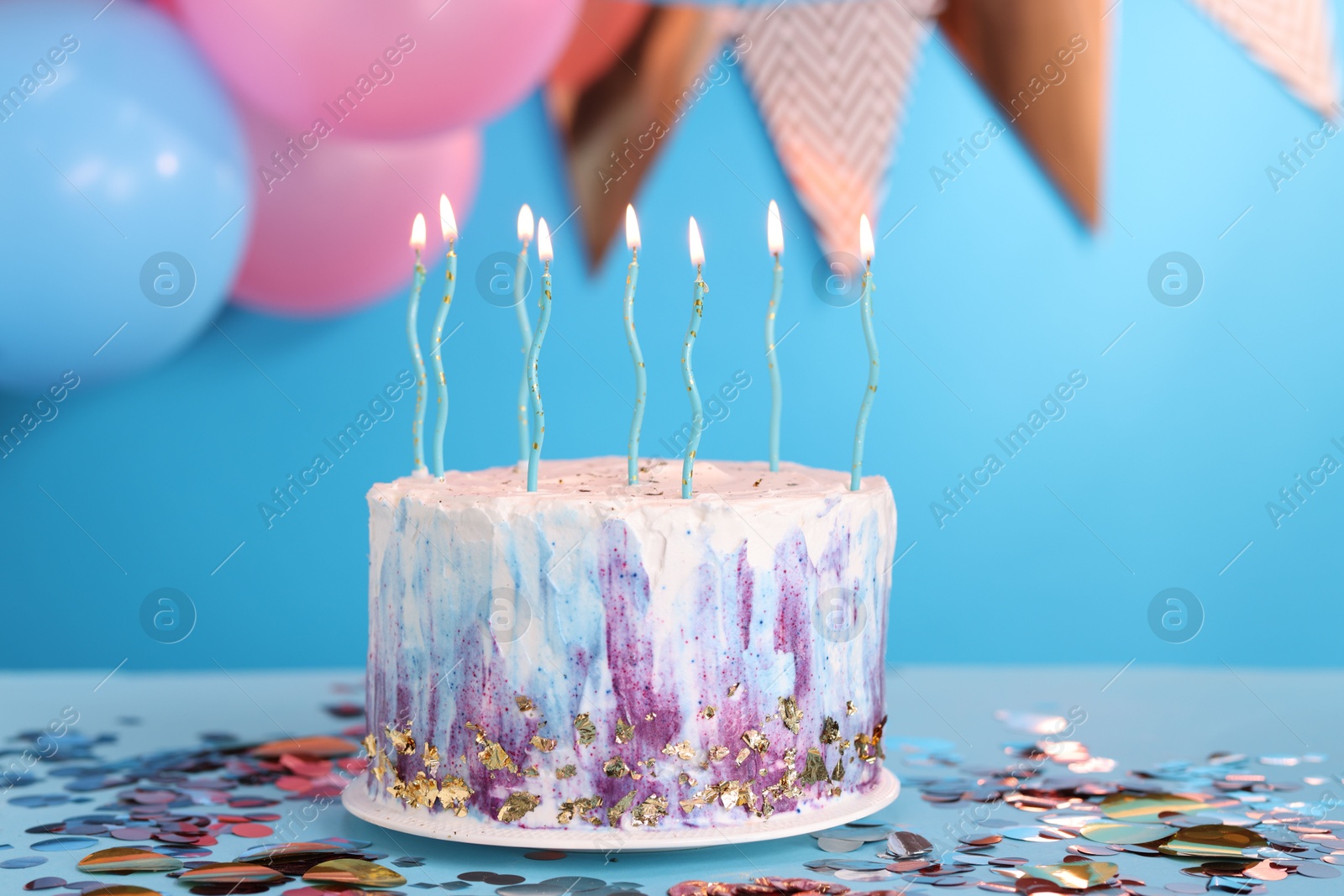 Photo of Tasty Birthday cake with burning candles and confetti on light blue table