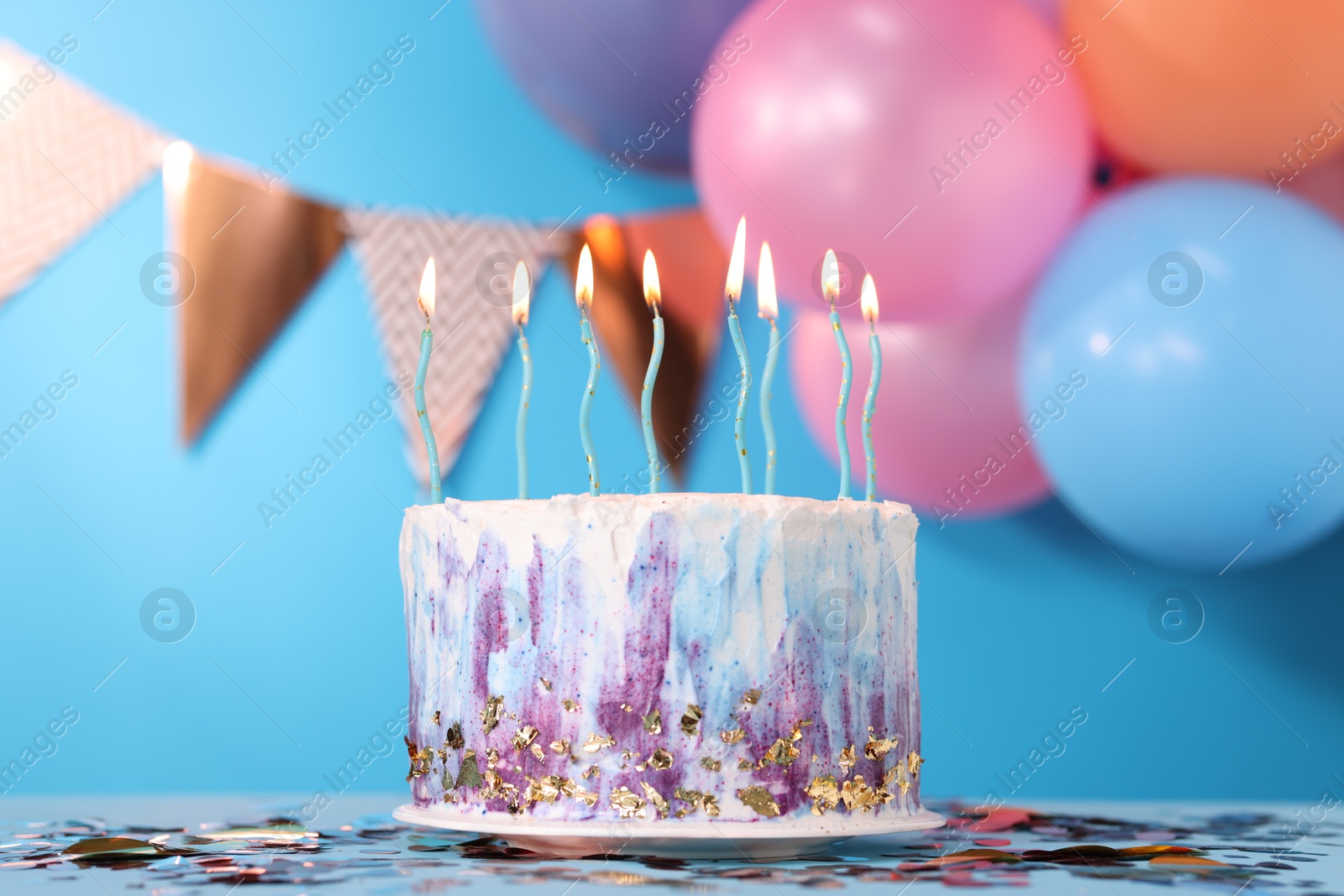 Photo of Tasty Birthday cake with burning candles and confetti on light blue table