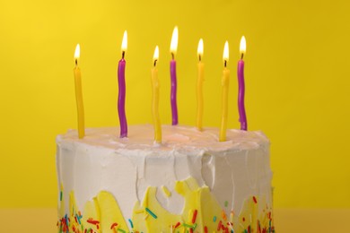 Photo of Tasty Birthday cake with burning candles on yellow background, closeup