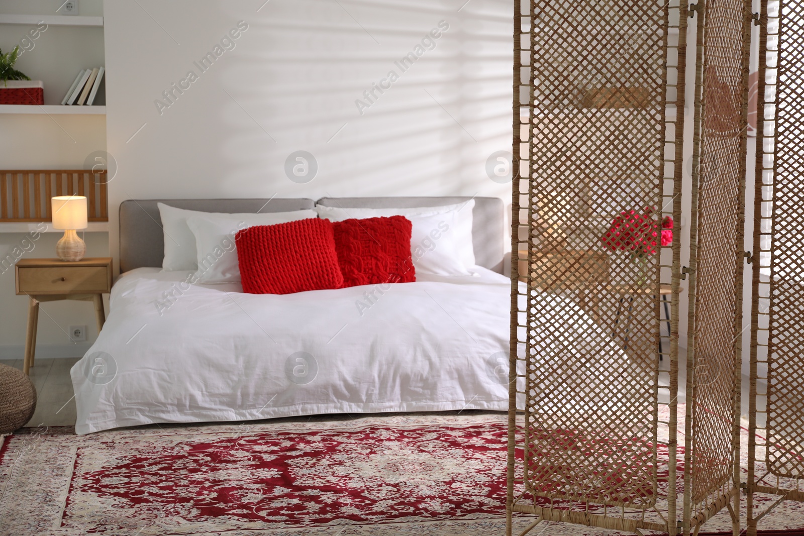 Photo of Beautiful folding screen, carpet and large bed in bedroom. Interior design