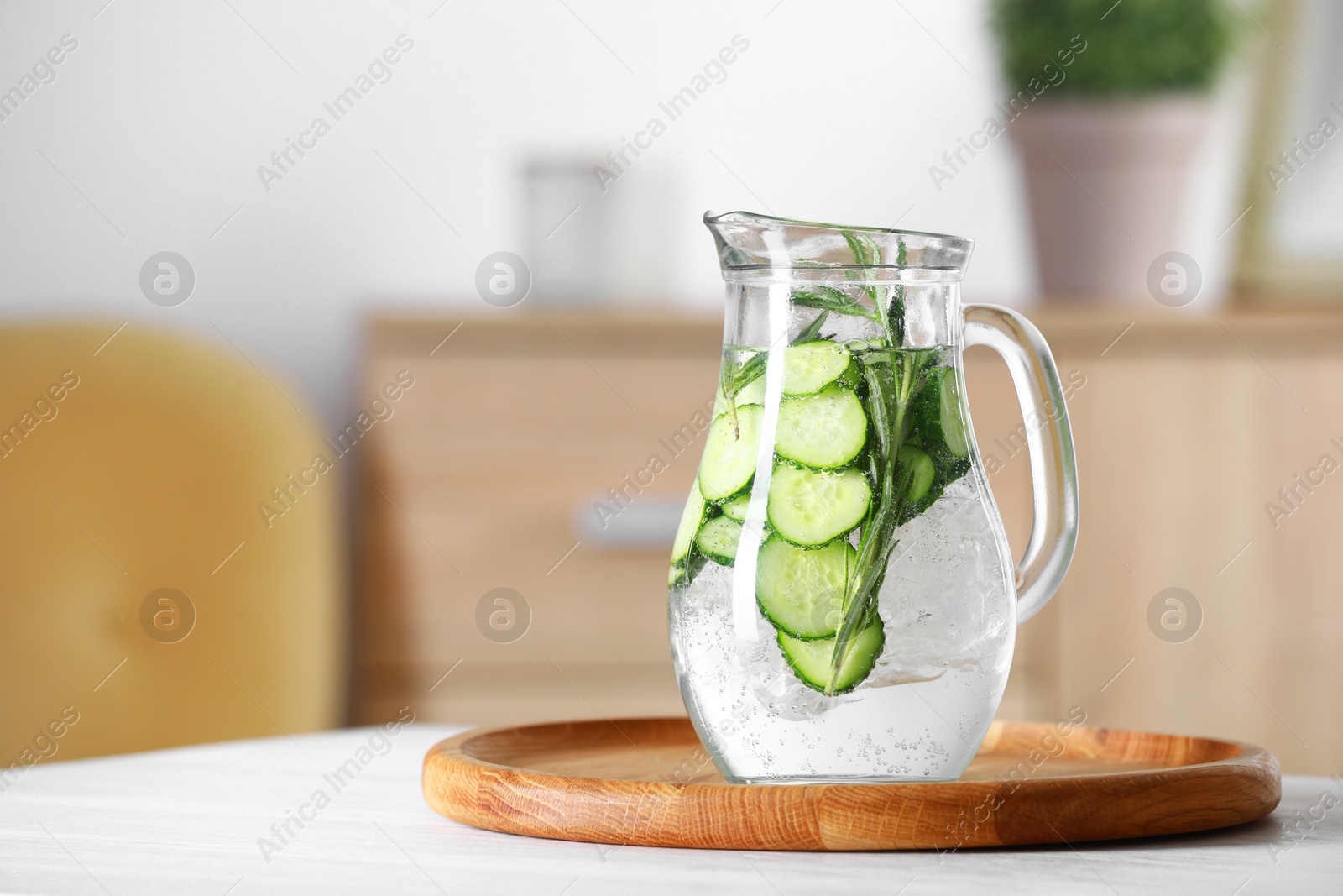 Photo of Refreshing cucumber water with rosemary in jug on white table. Space for text