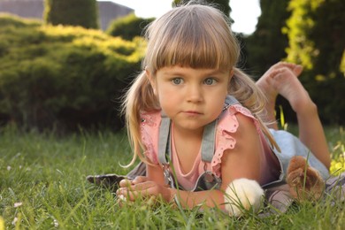 Little girl with cute chicks on green grass outdoors