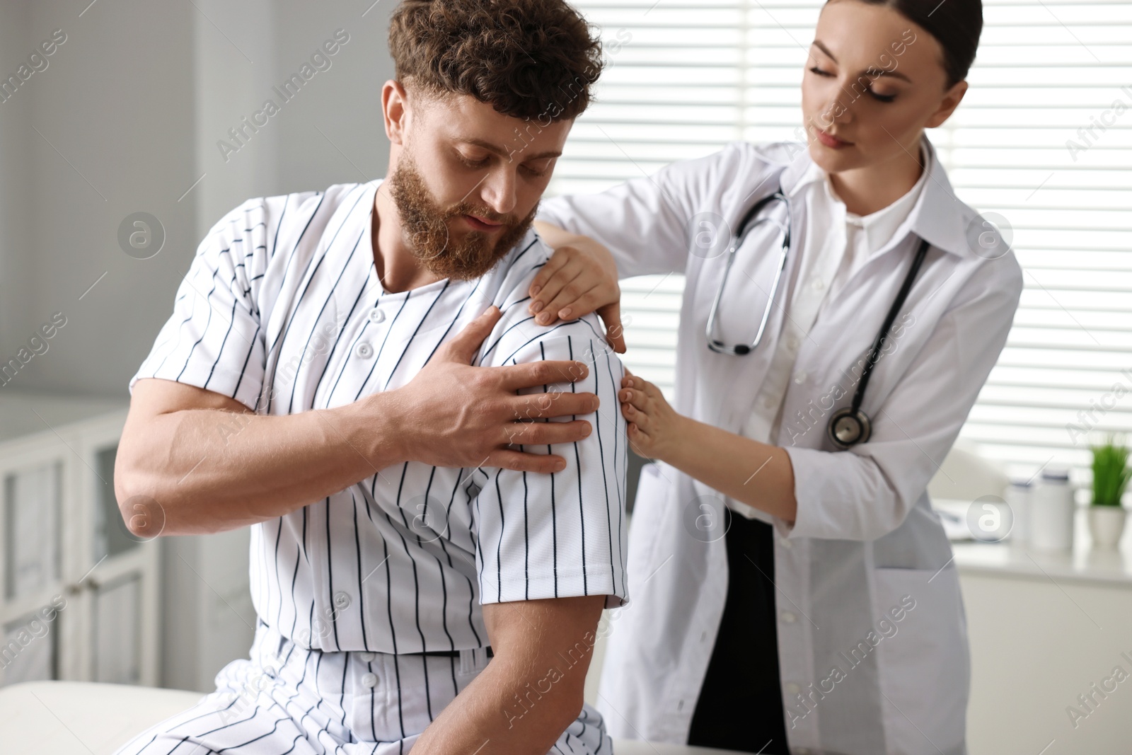 Photo of Sports injury. Doctor examining patient's shoulder in hospital