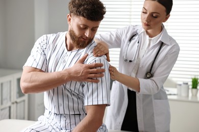 Sports injury. Doctor examining patient's shoulder in hospital