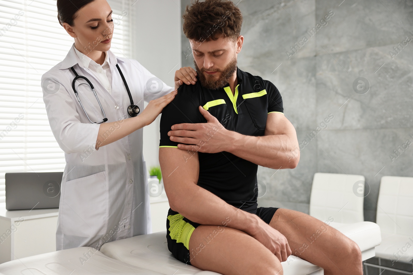 Photo of Sports injury. Doctor examining patient's shoulder in hospital