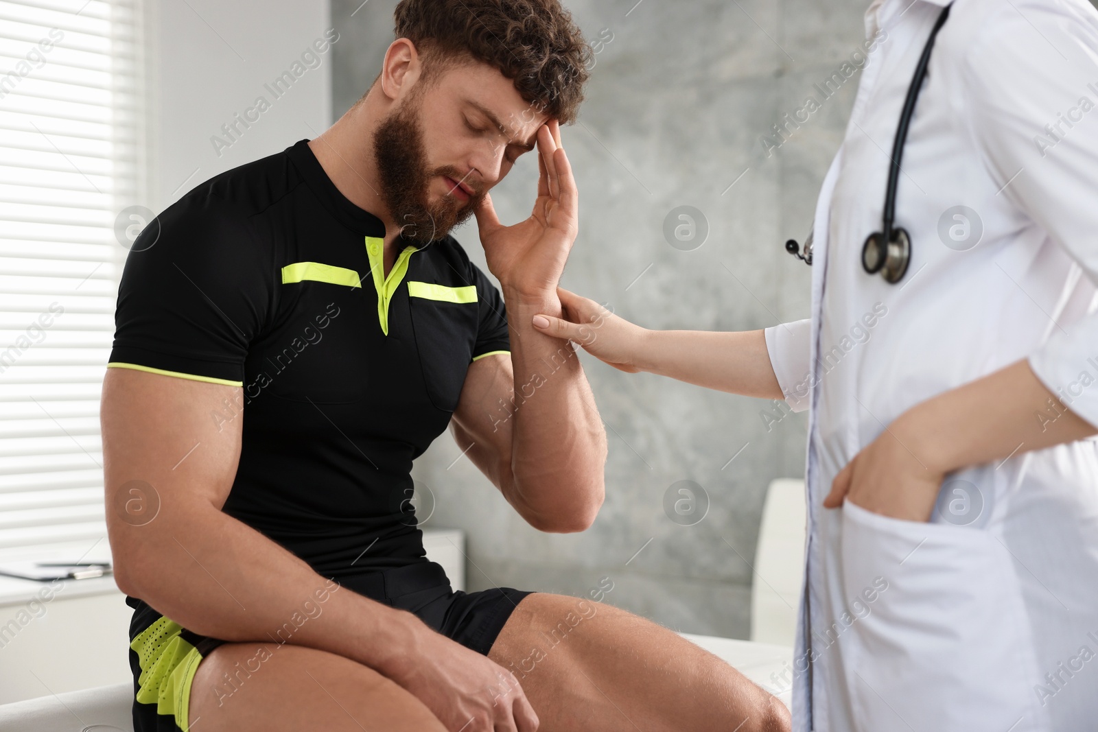 Photo of Doctor examining injured sportsman in hospital, closeup