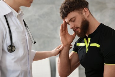 Photo of Doctor examining injured sportsman in hospital, closeup