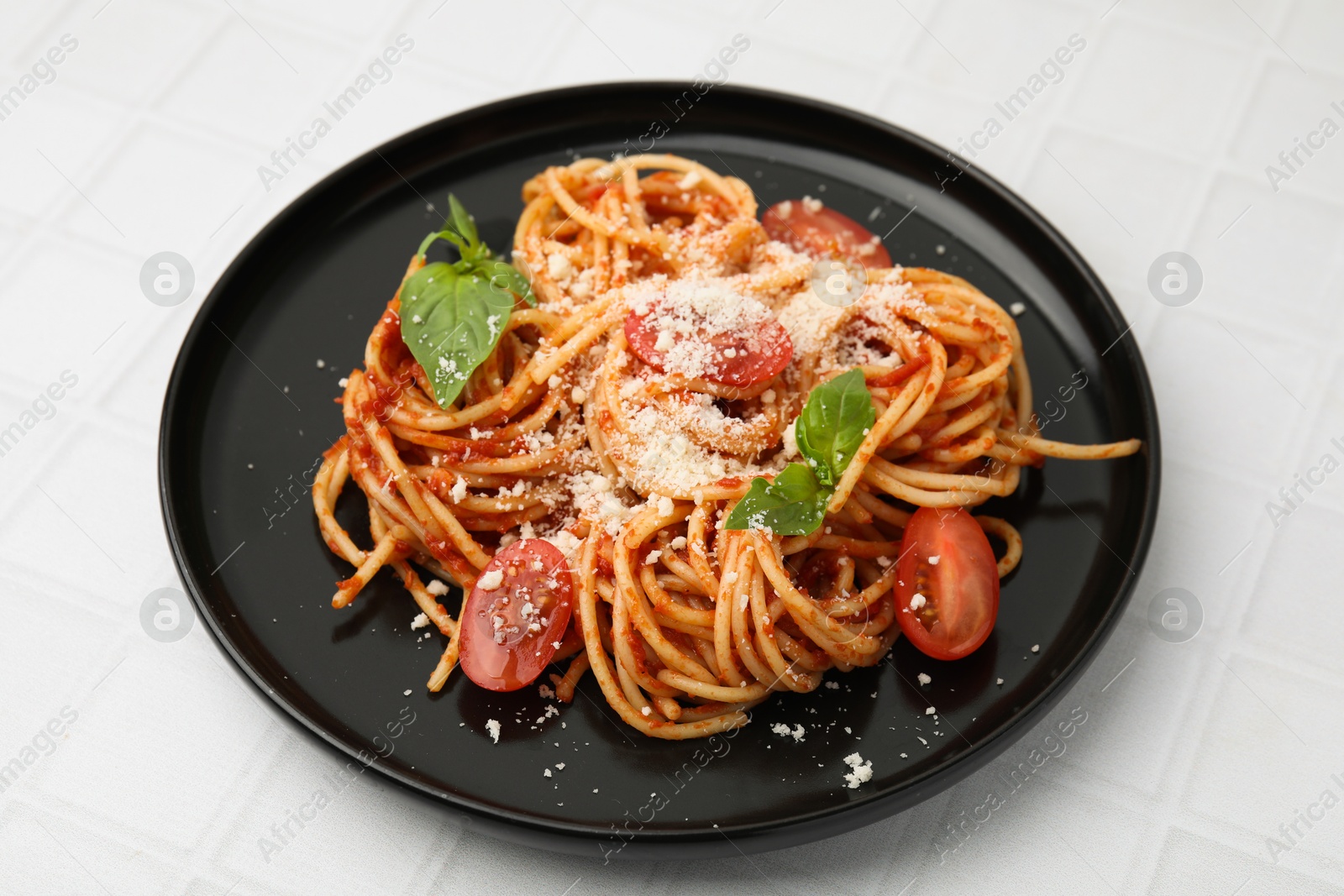 Photo of Tasty pasta with tomato sauce, cheese and basil on white tiled table