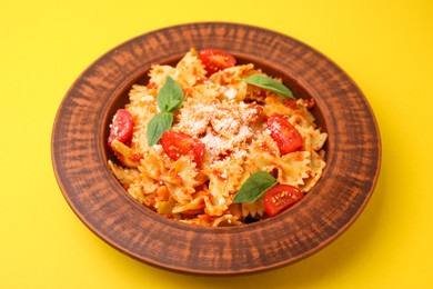 Tasty pasta with tomato, cheese and basil on yellow table