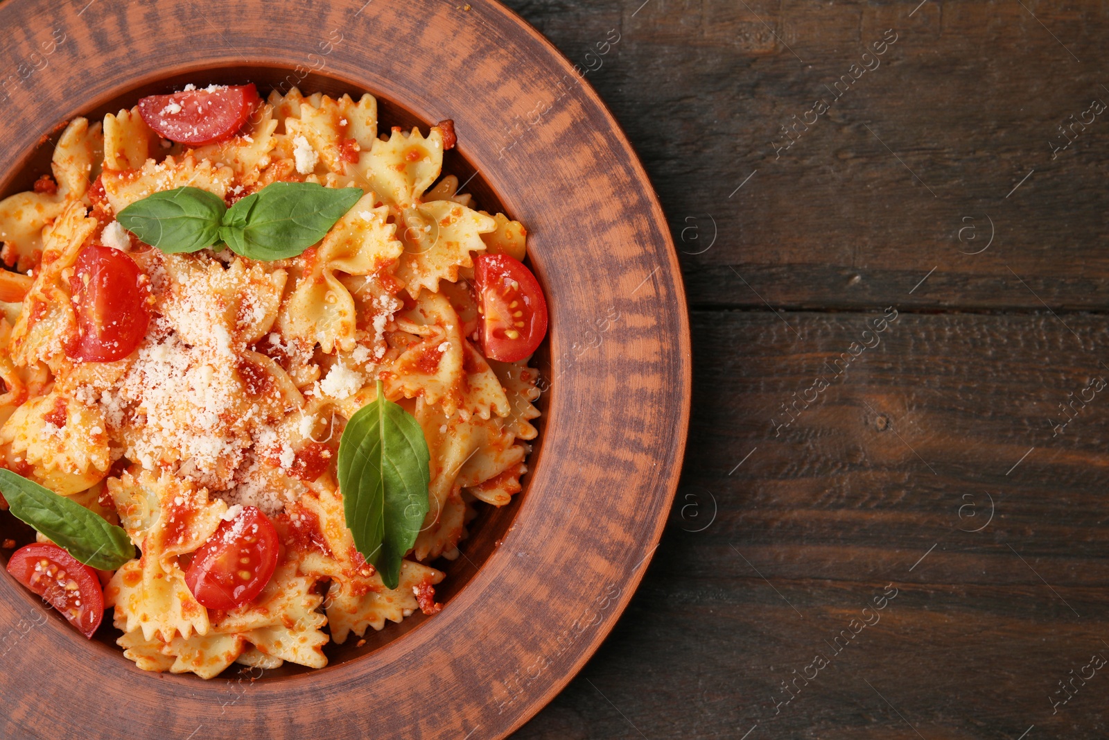 Photo of Tasty pasta with tomato, cheese and basil on wooden table, top view. Space for text