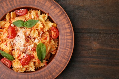 Photo of Tasty pasta with tomato, cheese and basil on wooden table, top view. Space for text