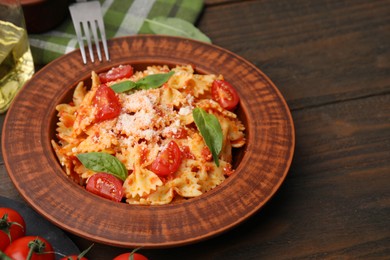 Photo of Tasty pasta with tomato, cheese and fork on wooden table, closeup