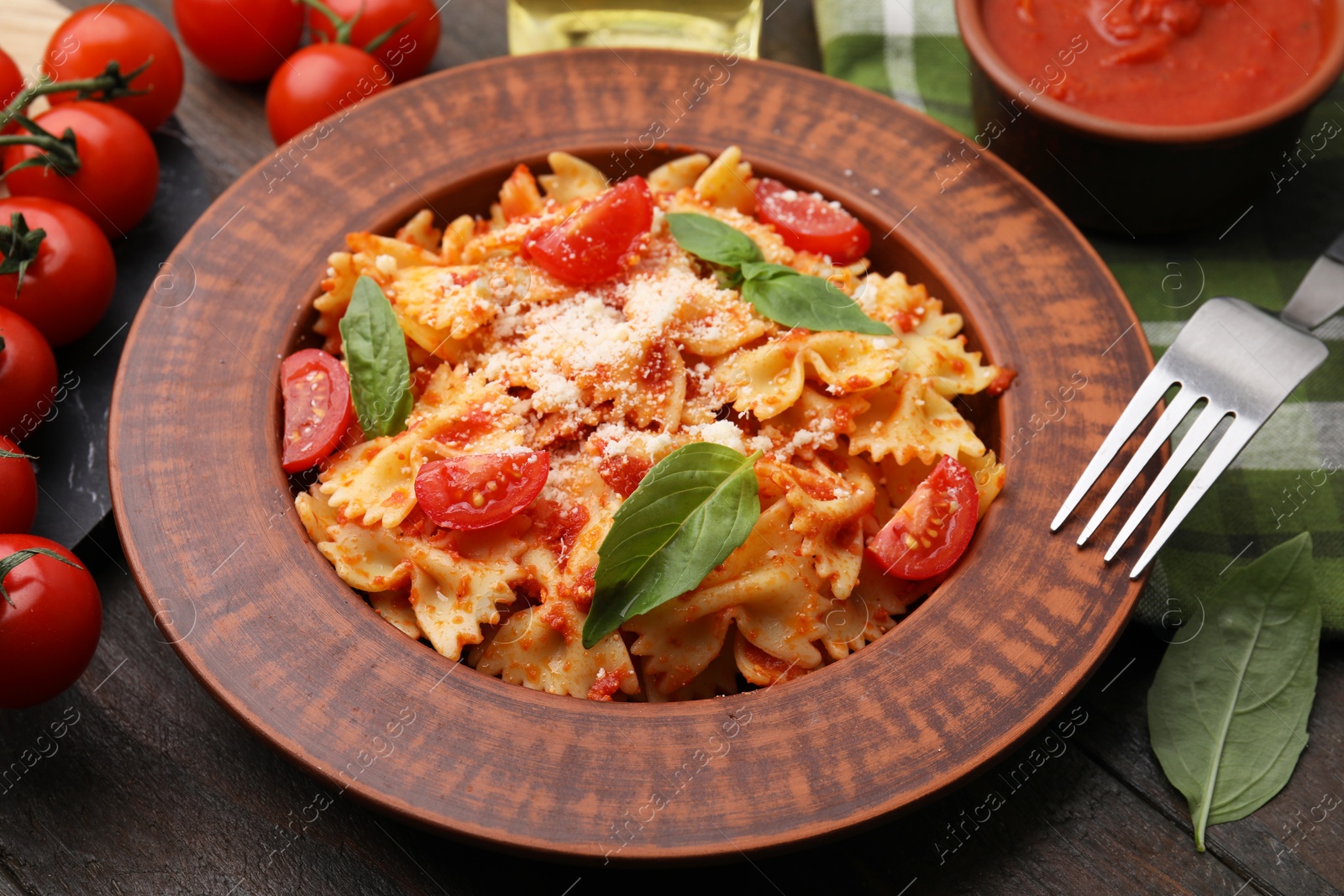 Photo of Tasty pasta with tomato, cheese and fork on wooden table, closeup