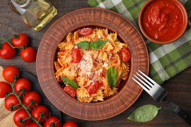 Tasty pasta with tomato sauce, cheese and basil served on wooden table, flat lay