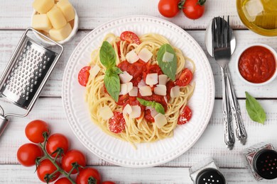 Tasty pasta with tomato sauce, cheese and basil served on white wooden table, flat lay