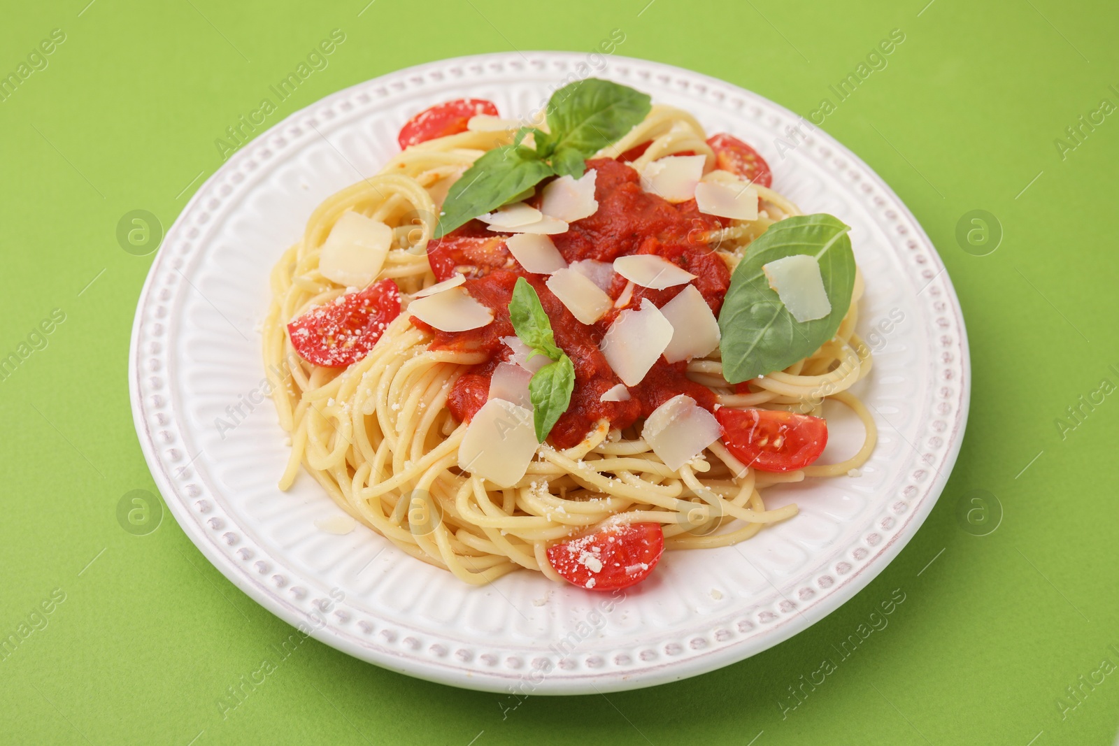 Photo of Tasty pasta with tomato sauce, cheese and basil on green table