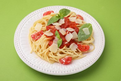 Tasty pasta with tomato sauce, cheese and basil on green table