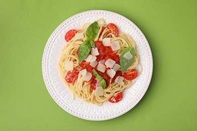 Photo of Tasty pasta with tomato sauce, cheese and basil on green table, top view