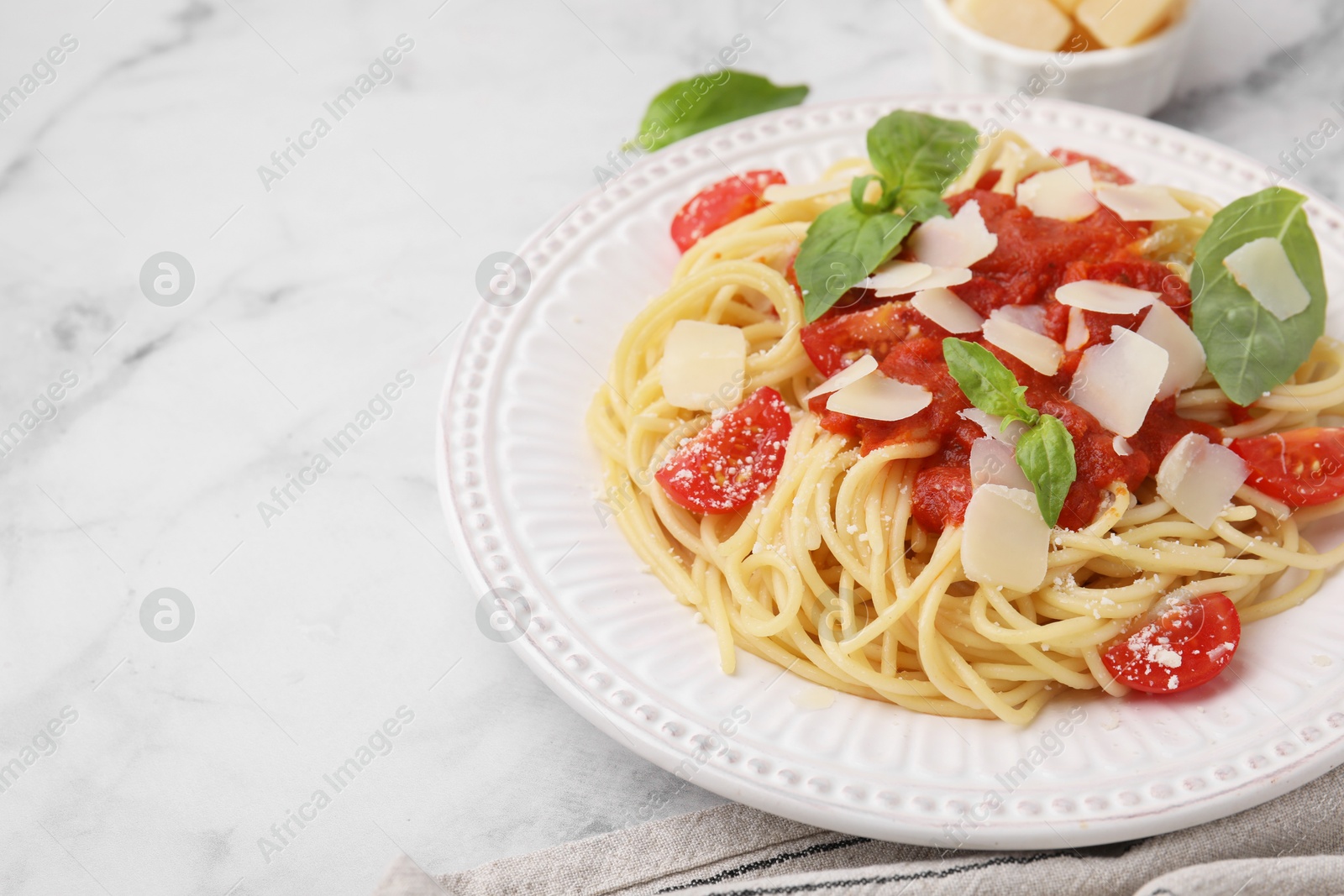 Photo of Tasty pasta with tomato sauce, cheese and basil on white marble table, closeup. Space for text