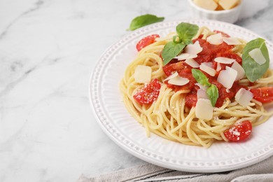 Tasty pasta with tomato sauce, cheese and basil on white marble table, closeup. Space for text