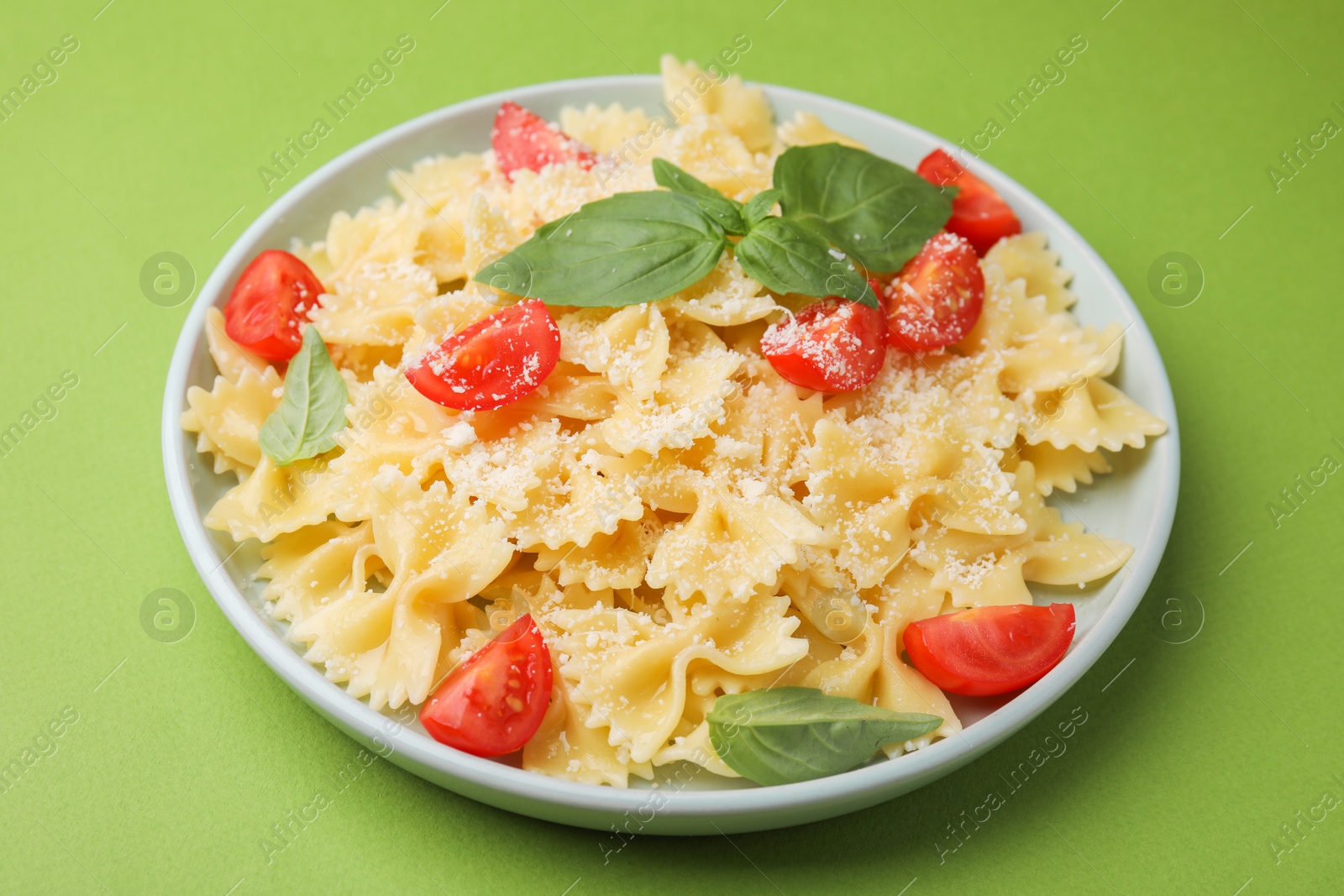 Photo of Tasty pasta with tomato, cheese and basil on green table