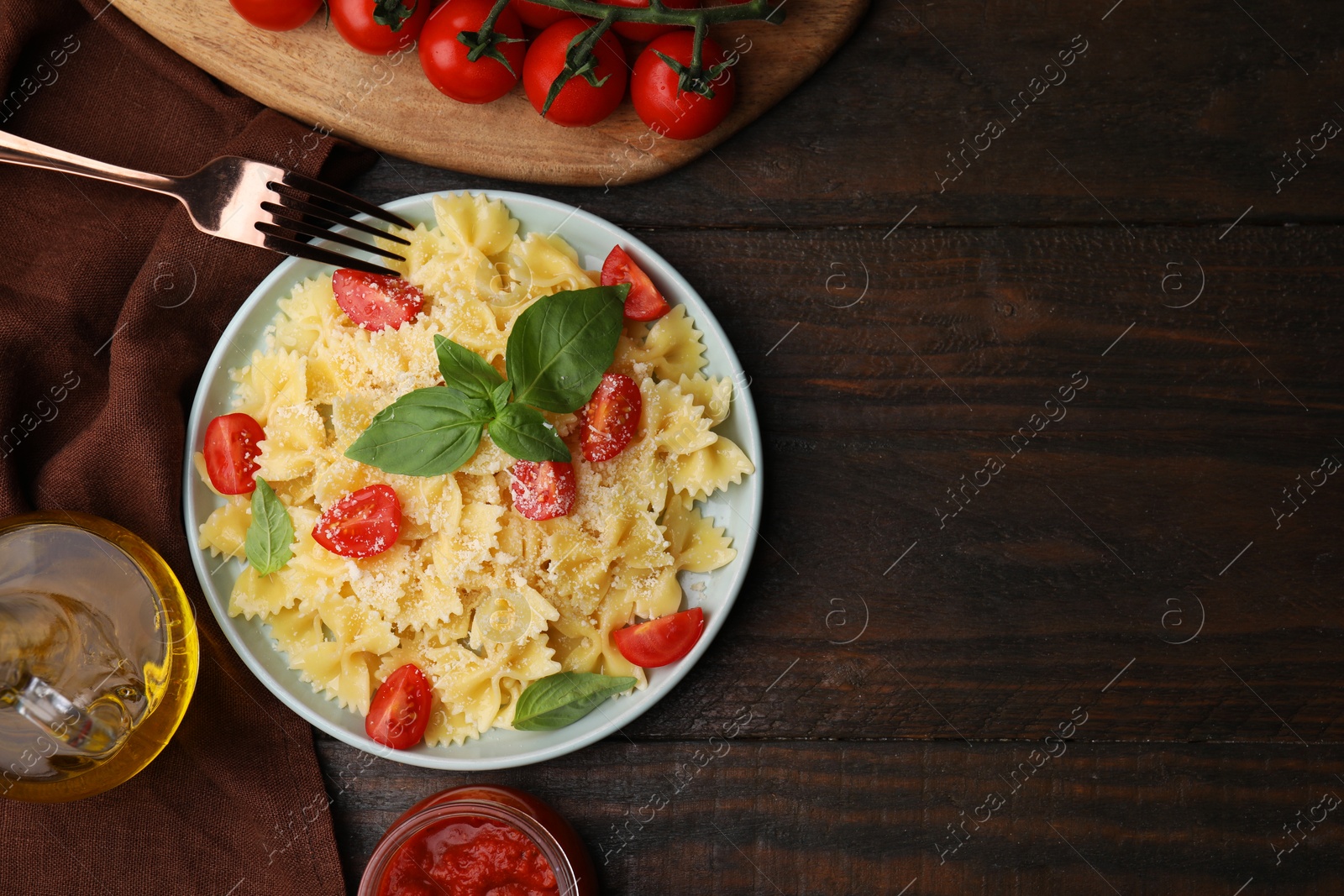 Photo of Tasty pasta with tomato, cheese and basil served on wooden table, flat lay. Space for text