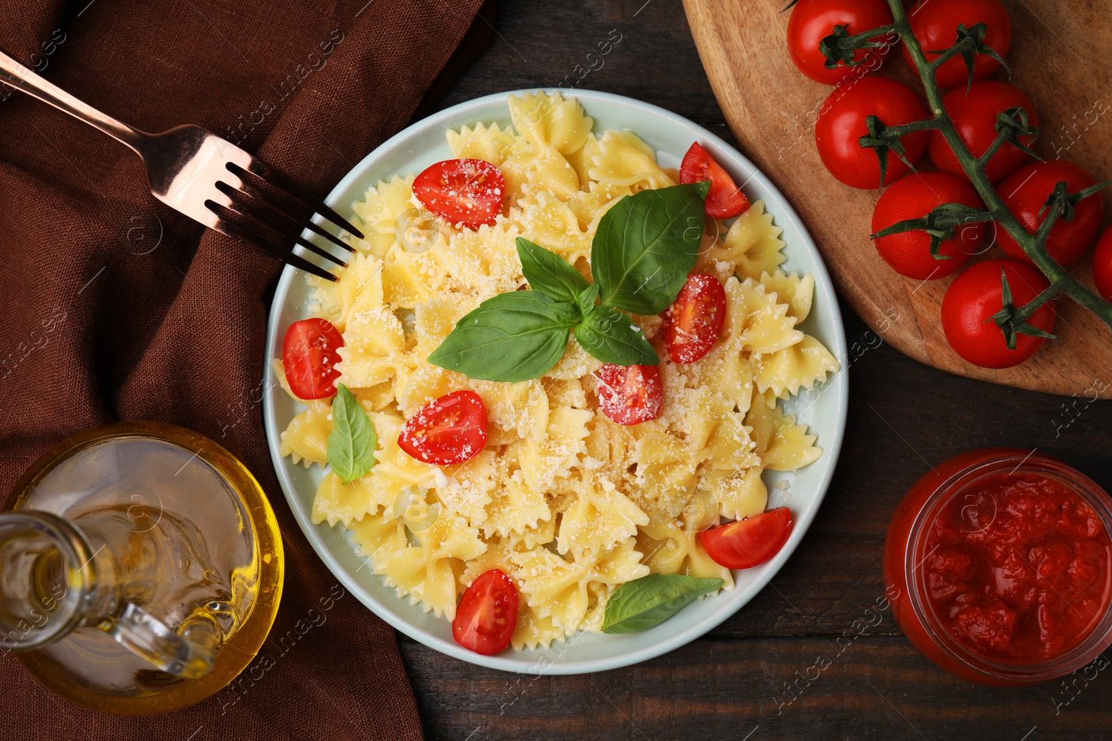 Photo of Tasty pasta with tomato, cheese and basil served on wooden table, flat lay