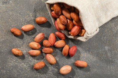 Fresh unpeeled peanuts and sack on grey table