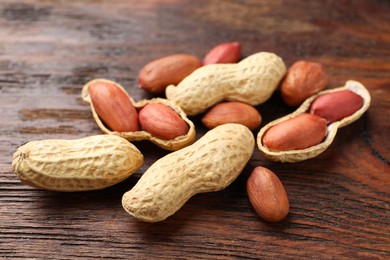 Fresh unpeeled peanuts on wooden table, closeup