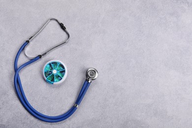 Photo of Stethoscope and pills on gray background, flat lay with space for text. Medical treatment