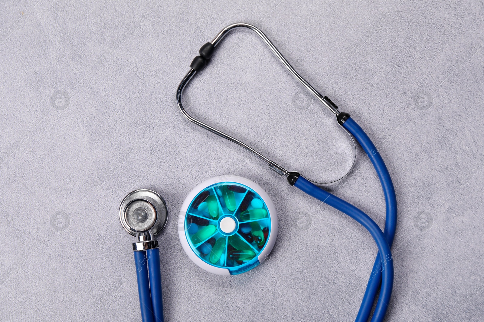 Photo of Stethoscope and pills on gray background, flat lay. Medical treatment